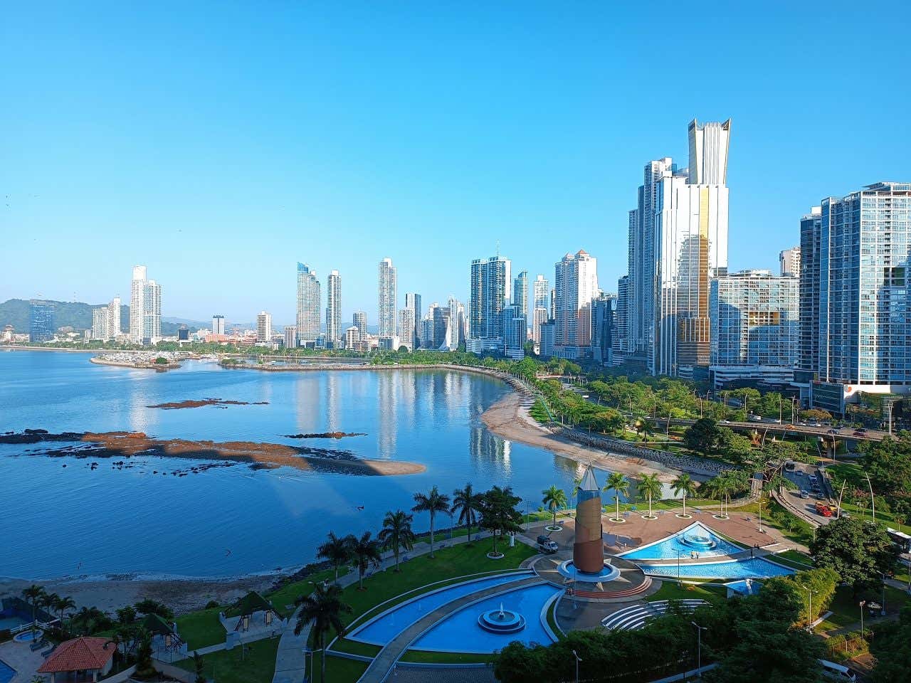 The skyscrapers of Panama city as seen from across a body of water, with a clear blue sky in the background.