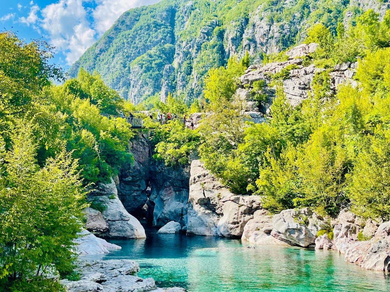 A shot of a lake or river in Blue Eye, with a cliff covered in vegetation in the background.