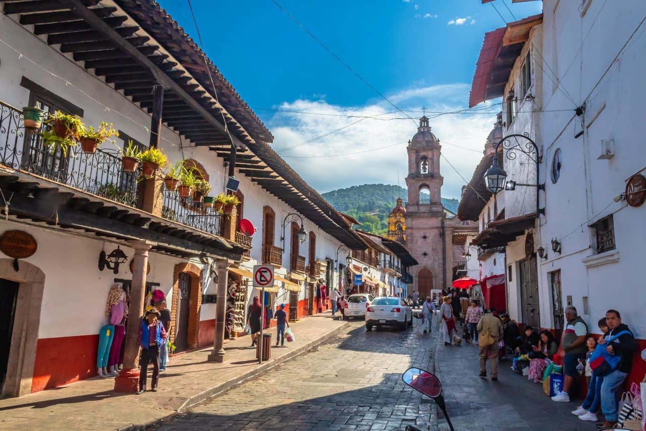 Valle de Bravo, with people standing along the street and a church campanile in the background.