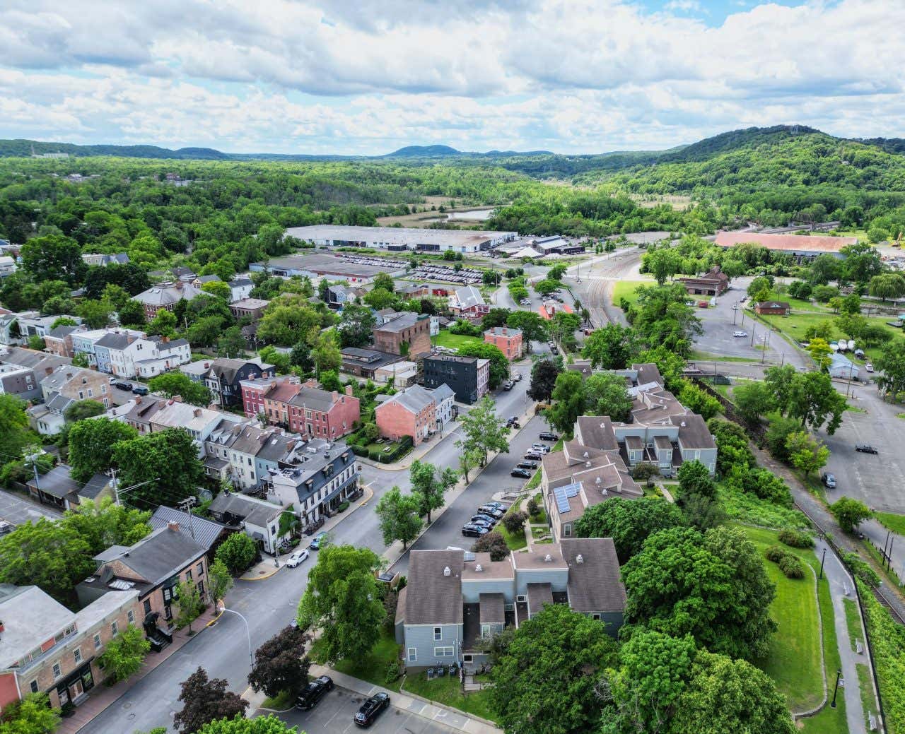 Aerial view of Hudson, NY, a small town with lots of green vegetation surrounding it.