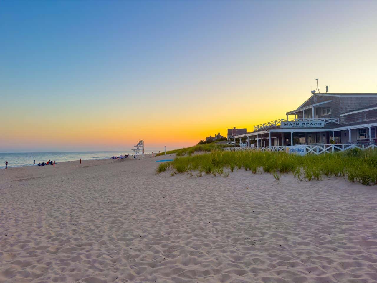 A beach in the Hamptons, NY with a blue and yellow sky in the background.