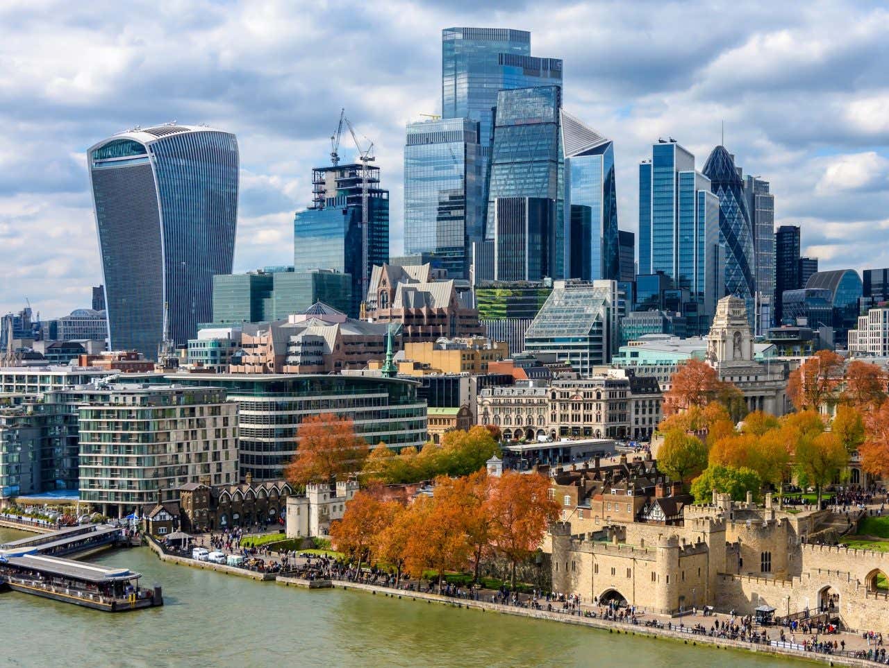 Skyline do distrito financeiro de Londres com diversos arranha-céus e a Torre de Londres à margem do rio