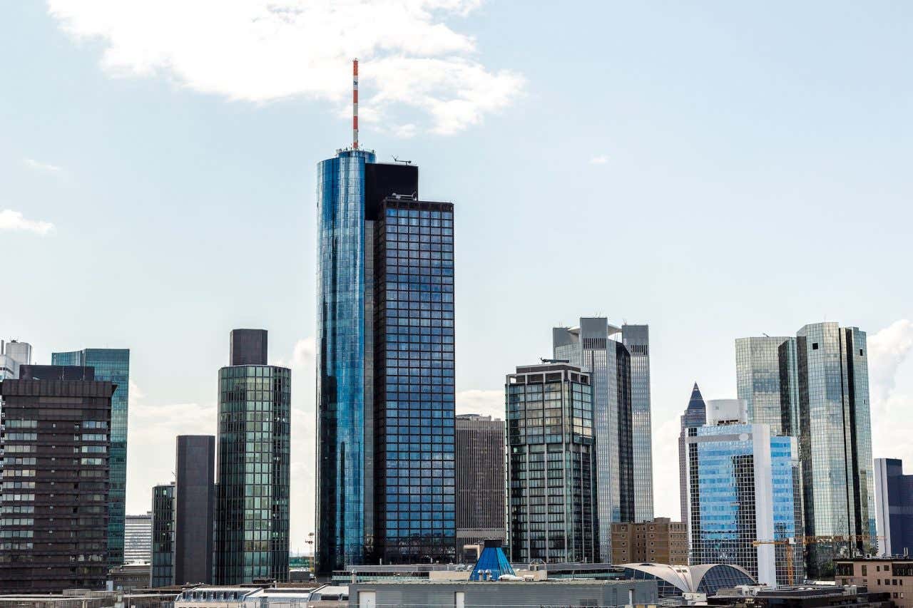 Main Tower, um prédio espelhado, rodeada de outros edifícios de Frankfurt em um dia nublado