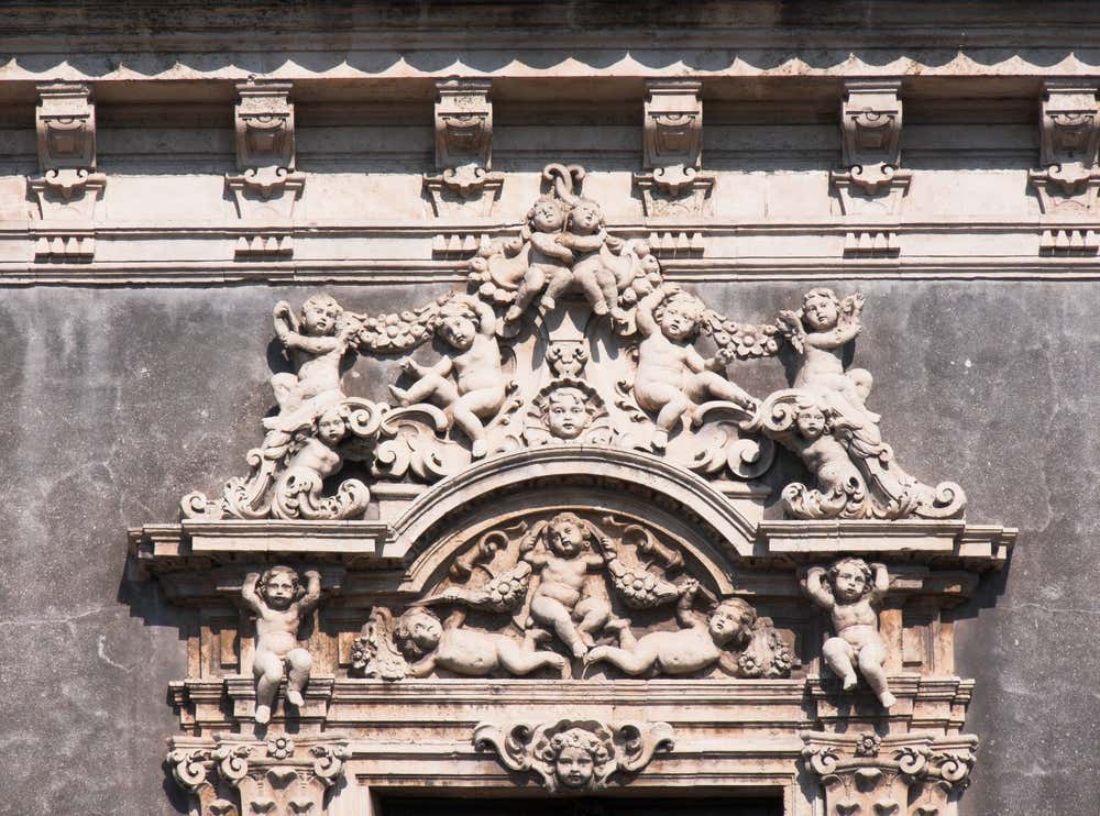 Un dettaglio decorativo della finestra di palazzo Biscari, con piccoli putti, motivi floreali scolpiti in pietra bianca