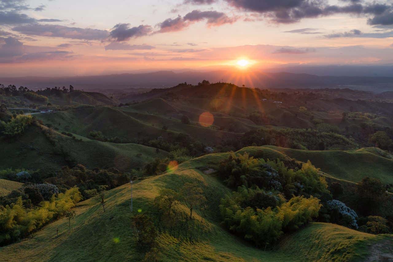 An expansive landscape in the Coffee Triangle with the sun setting in the background.