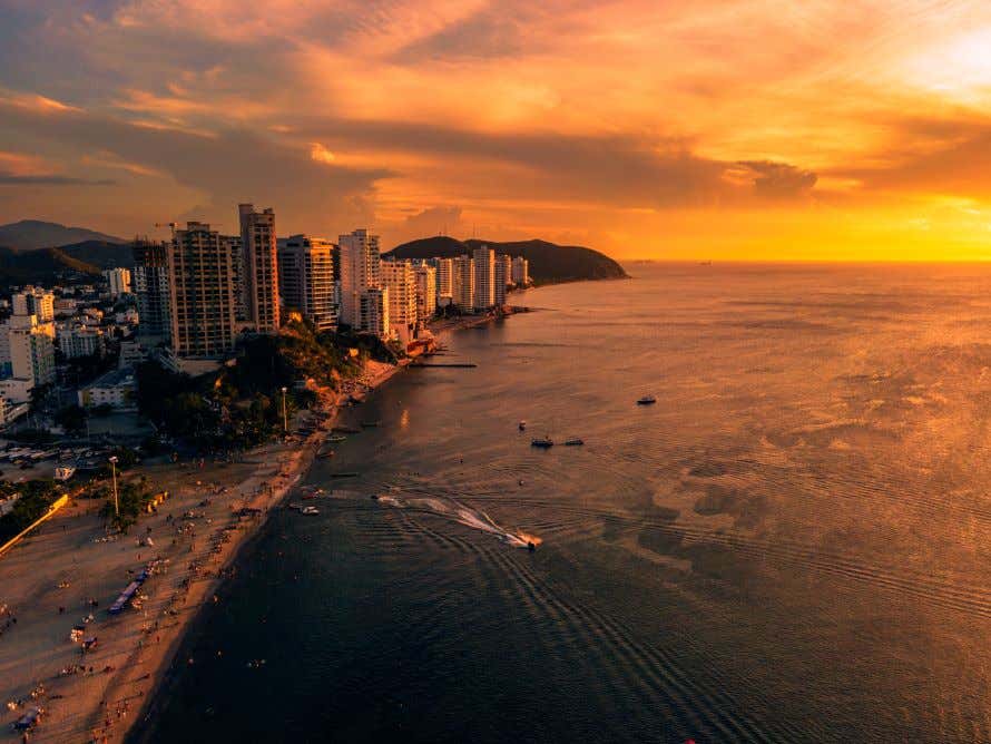 An aerial shot of Santa Marta, Colombia during the evening, with boats sailing around the bay. 