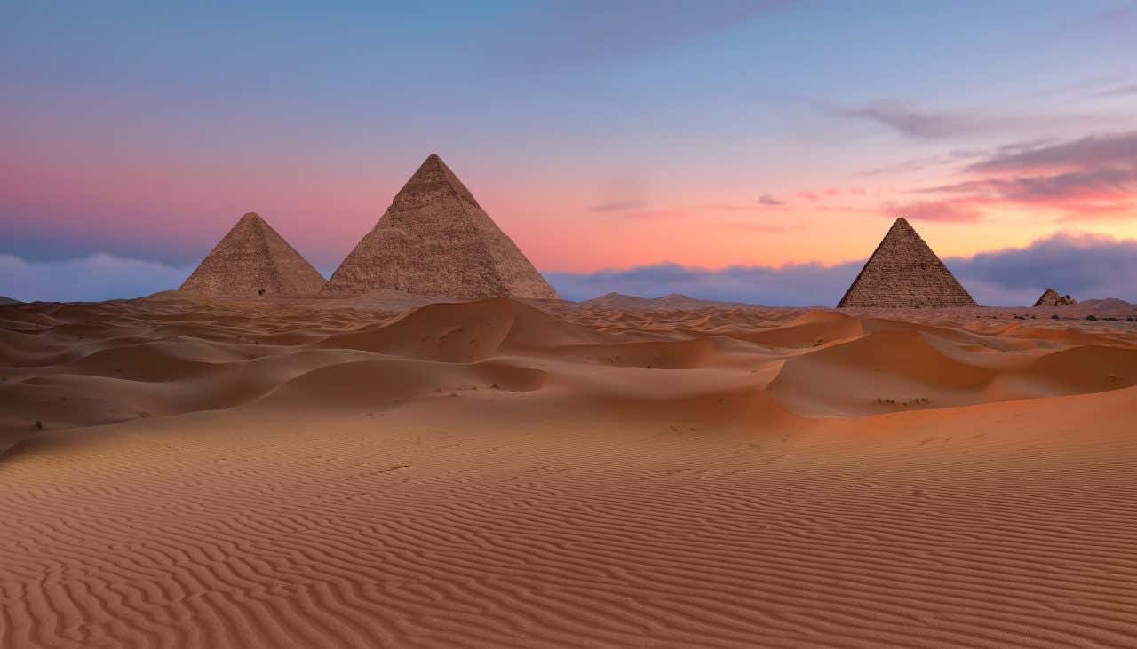 The Pyramids of Giza with a colorful sky in the background.