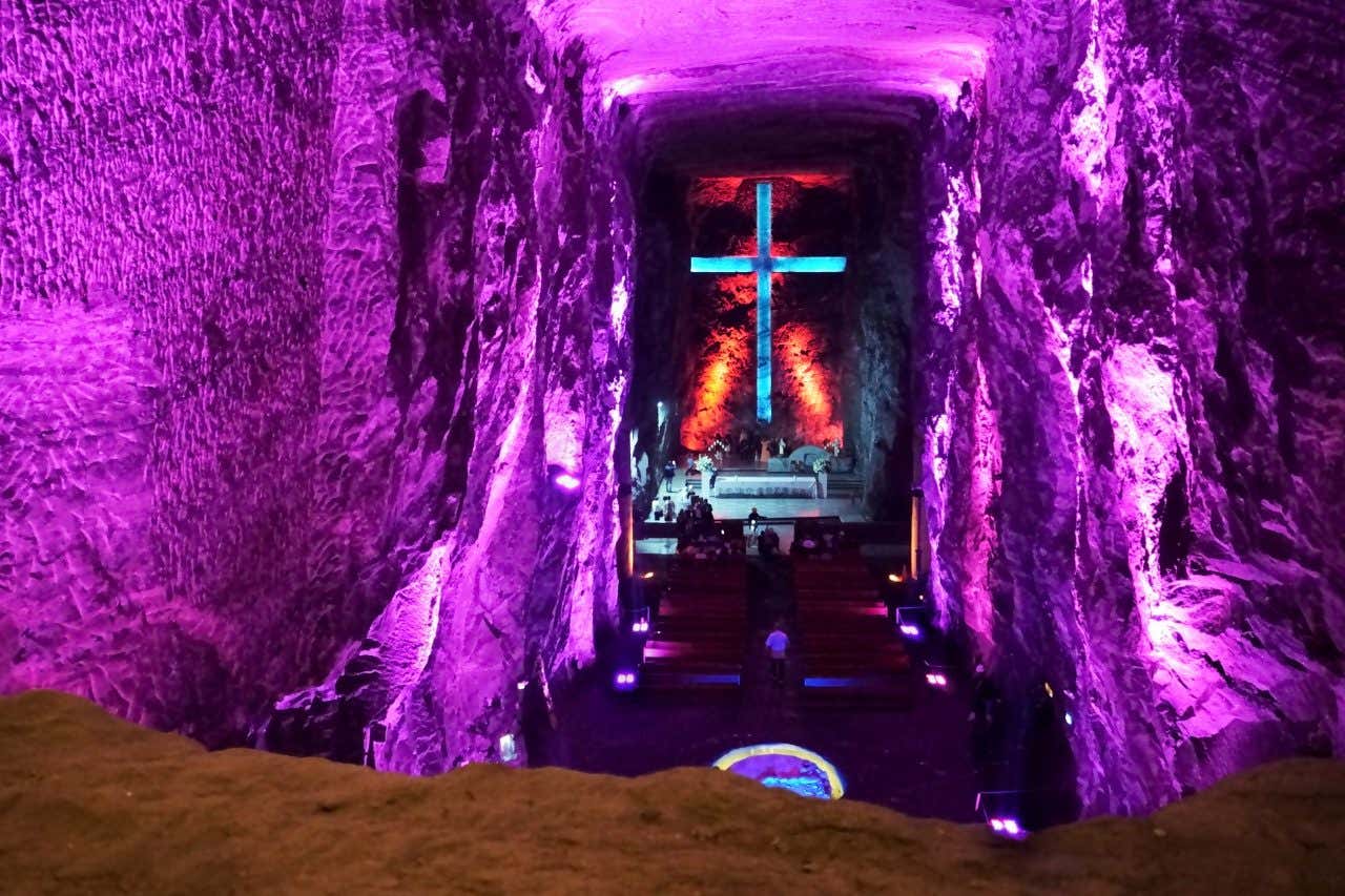 A shot of the inside of the Salt Cathedral of Zipaquirá, with a purple light coloring the room.