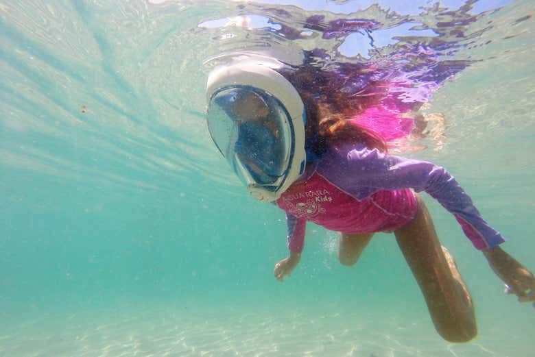 Criança fazendo snorkel na praia da Sepultura