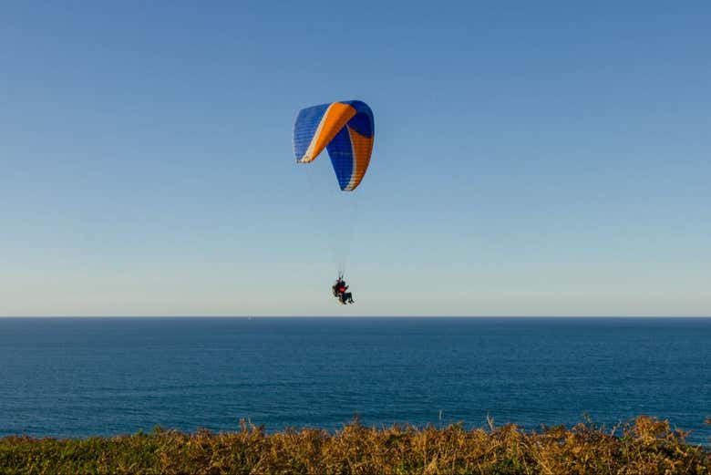 Un parapente volando con el mar de fondo