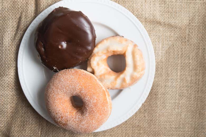 Une assiette de donuts au chocolat, avec glaçage et au sucre