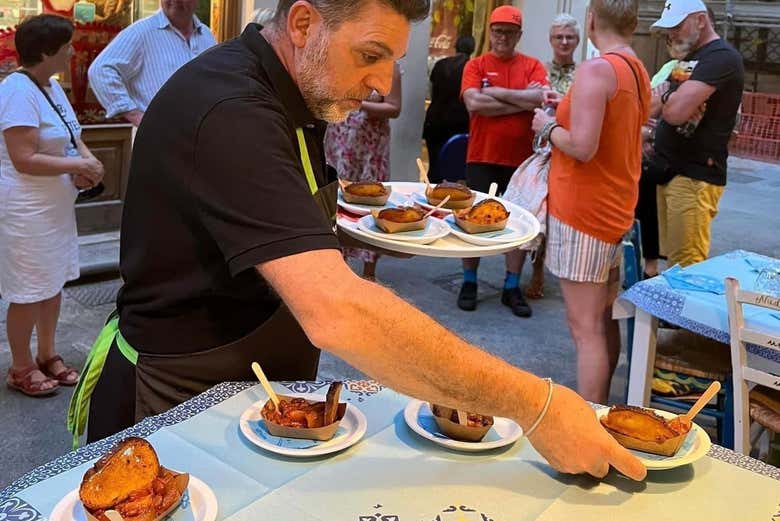 A waiter handing out plates of caponata trapanese