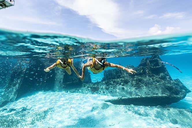 Um casal mergulhando próximo a um navio naufragado em Cancún